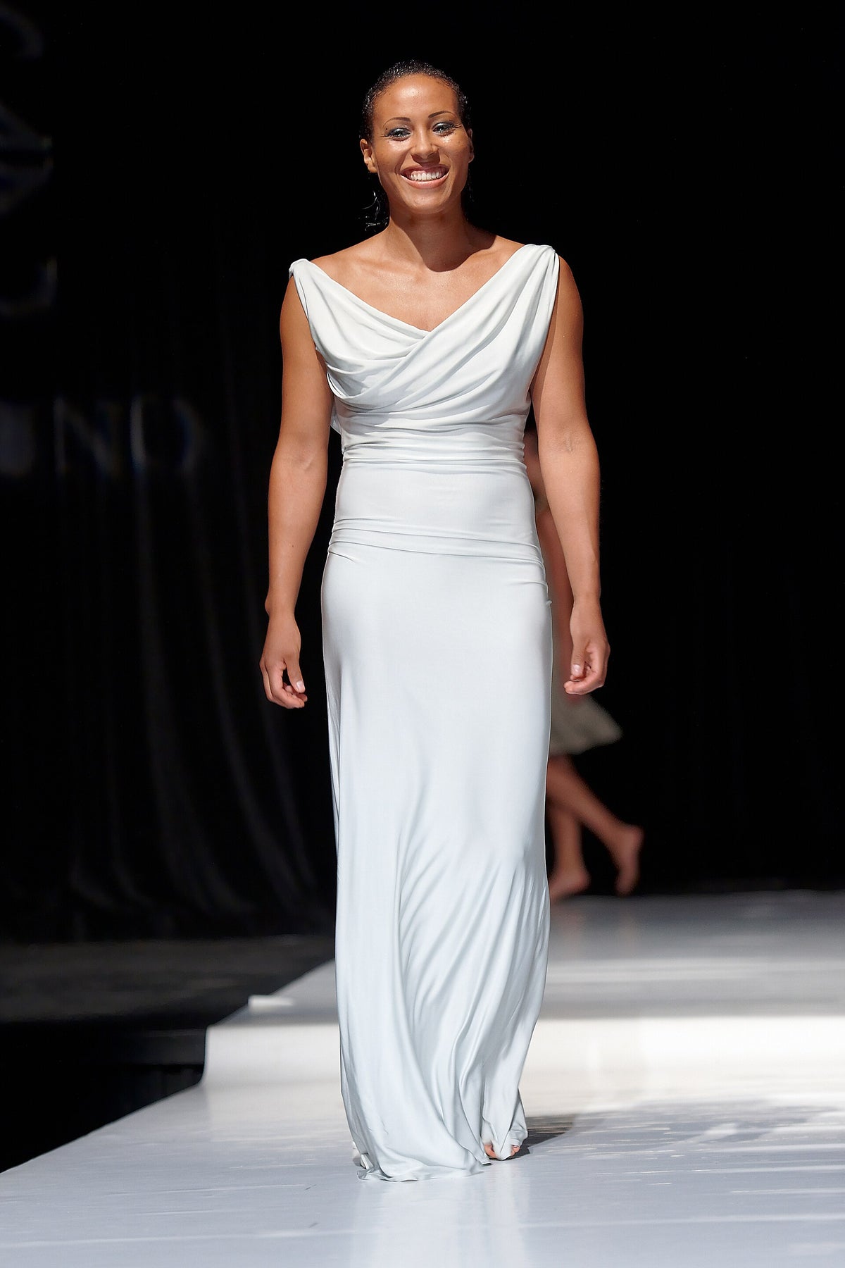 Cecilia Brækhus in een witte jurk op de catwalk van Oslo Fashion Show