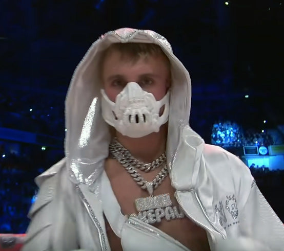 Jake Paul in een zilverkleurige capuchonjas met een wit masker