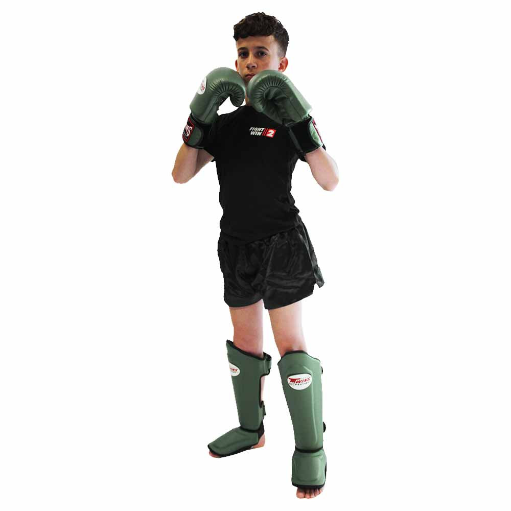 Jongen met groene Twins-bokshandschoenen en scheenbeschermers, een zwart kickboksbroekje en een zwart Fight2Win-shirt.